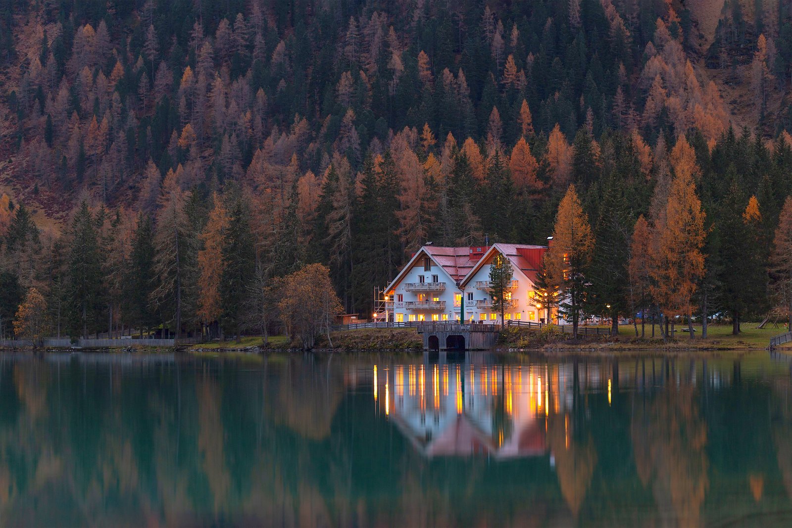 Sill Plate Builders. A framed lake house at dusk, lights on inside.