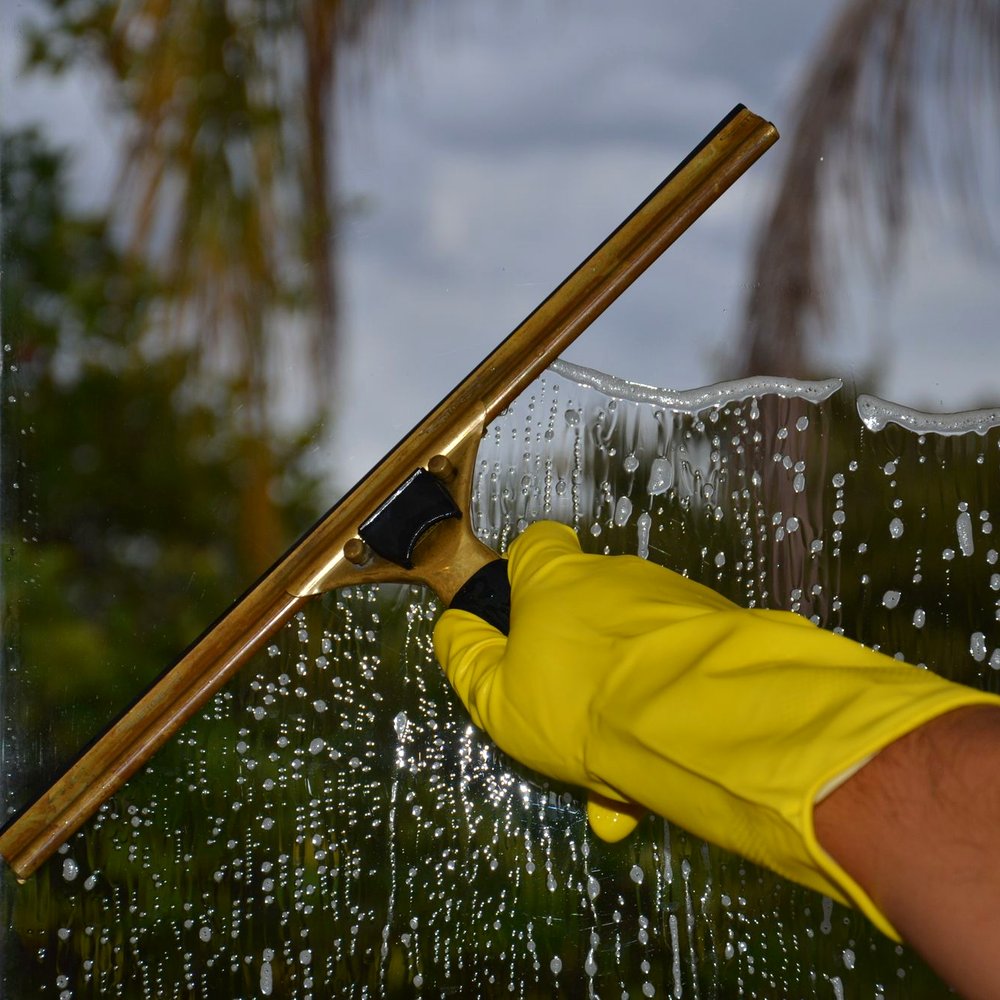 A professional window tool clearing premium floor-to-ceiling glass; no faces.