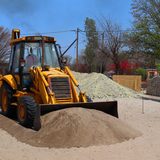 Hard Pan Excavation. A yellow backhoe on a job site.
