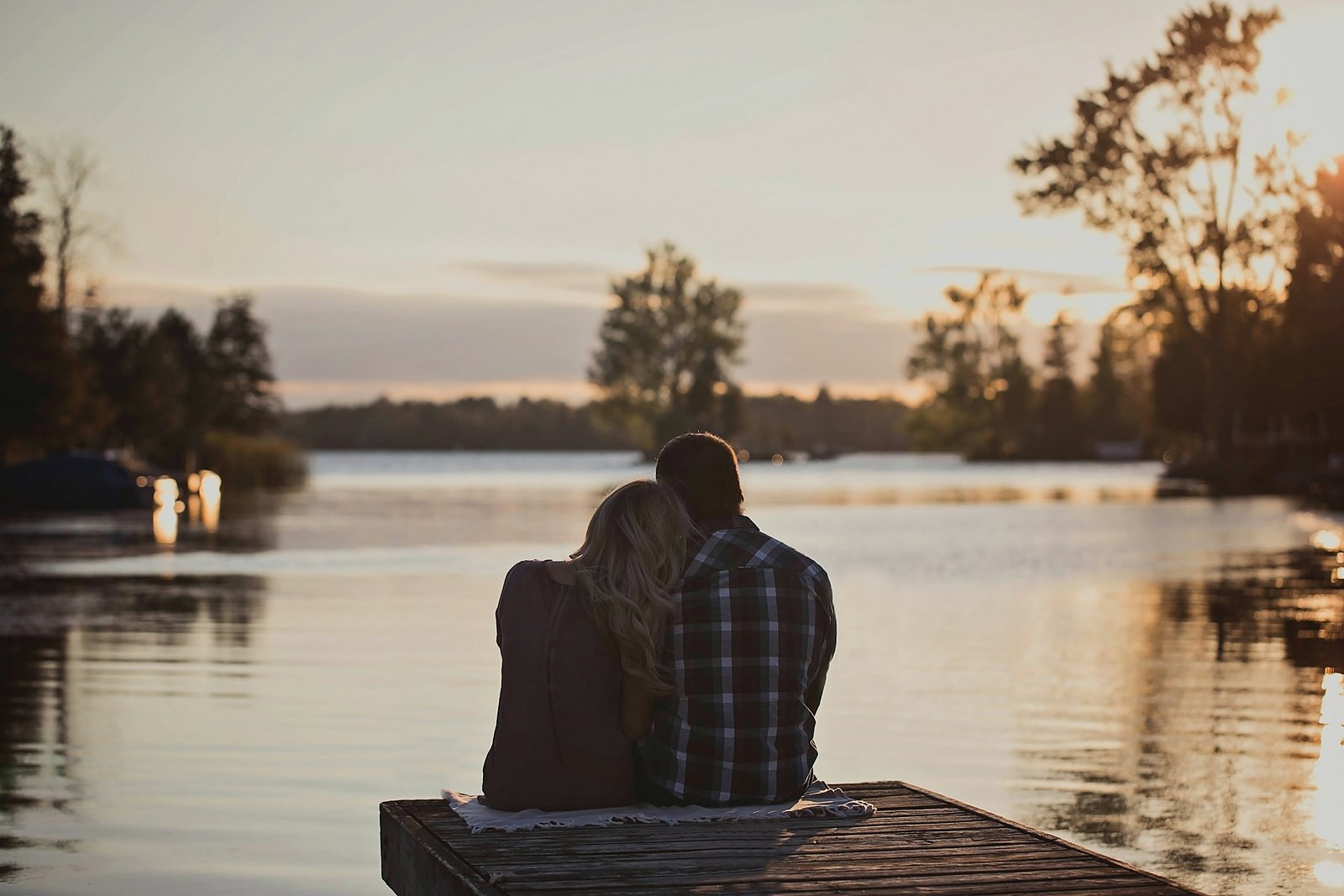 Couple sitting at the end of a dock at golden hour.