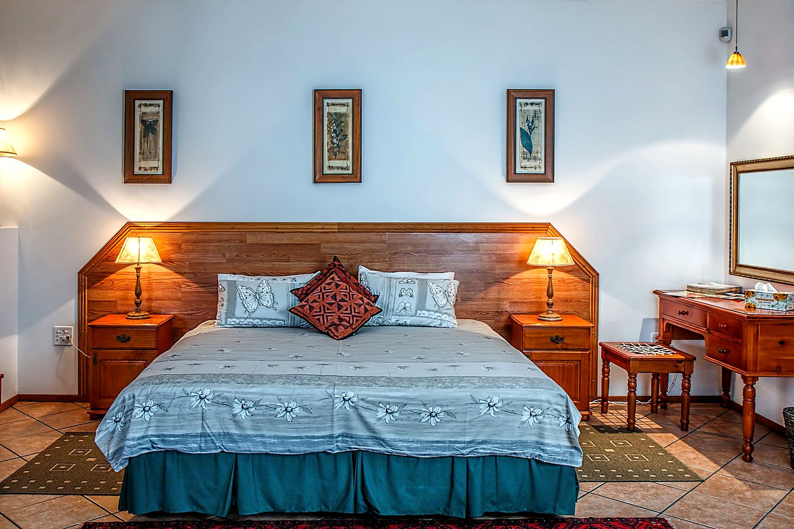 Neatly made boutique inn bed with wood headboard and warm bedside lamps.