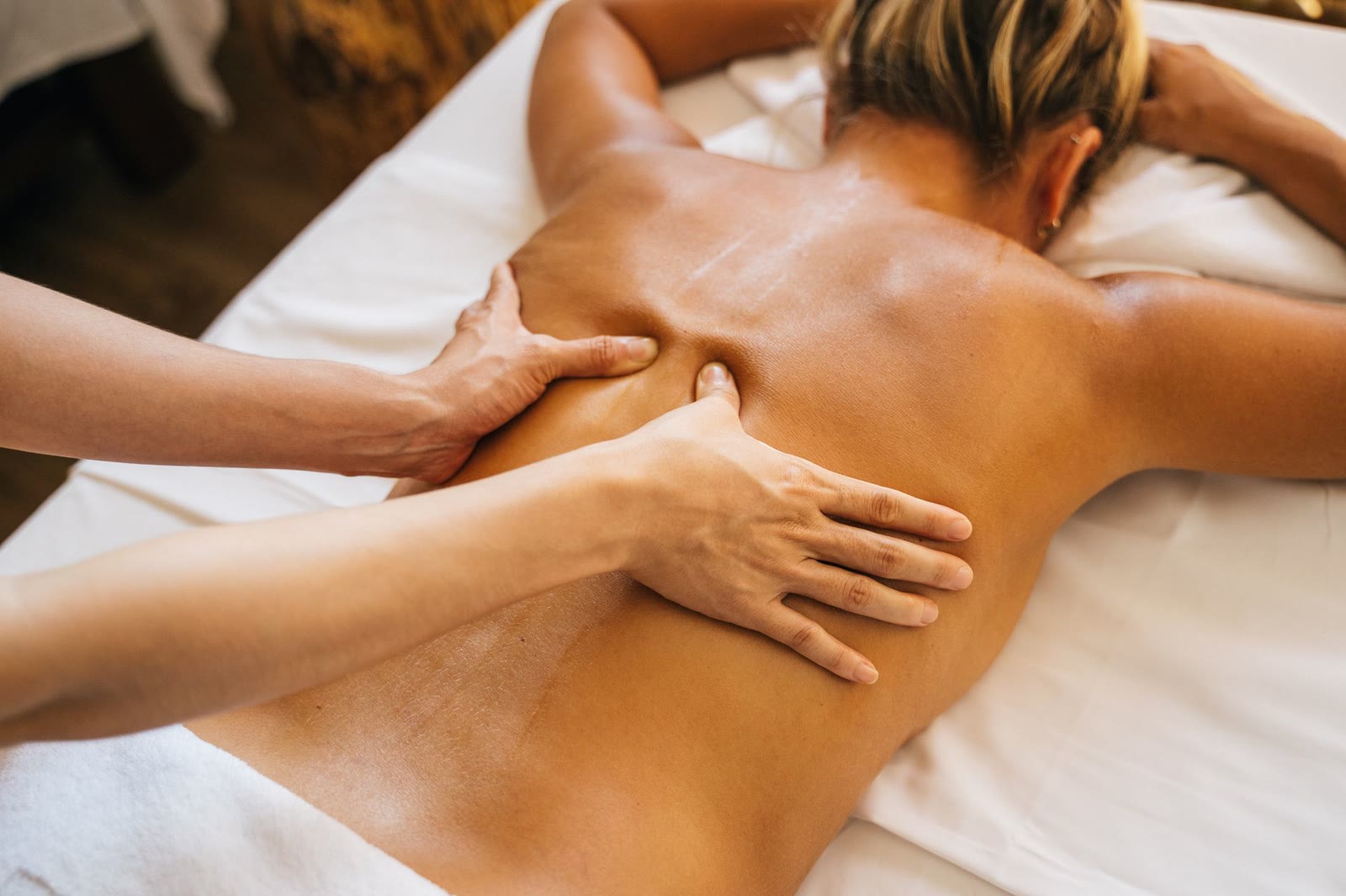Therapist hands applying focused pressure along the upper back.